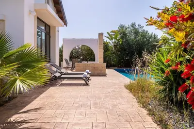 a patio with a bench and a swimming pool at Lumina 2-Bedroom Villa and Pool in Ayia Napa in Ayia Napa
