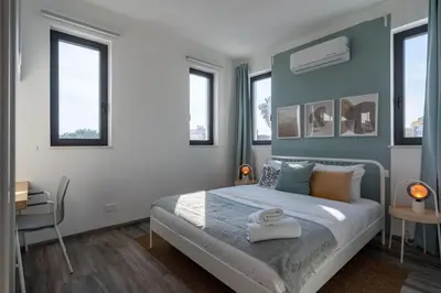 a bedroom with a bed with blue walls and windows at Thálassa 2-Bedroom Apartment in Larnaca in Larnaka