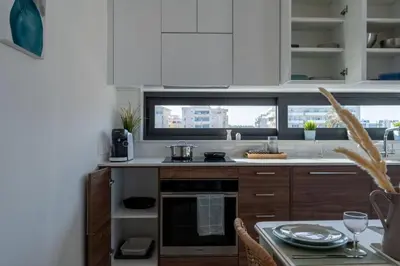 a kitchen with white cabinets and a table with dishes on it at Thálassa 2-Bedroom Apartment in Larnaca in Larnaka