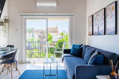a living room with a blue couch and a balcony at Lazuli Stylish 1-BR Apt W Pool & Balcony in Larnaca in Voroklini