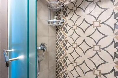 a shower with a shower head in a bathroom at Maryam's 2-BR Apt Facing Larnaca Harbor With Pool in Larnaka