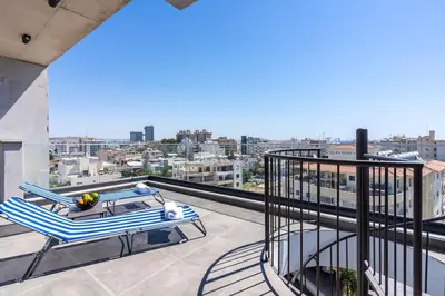 a balcony with a table and chairs on top of a building at Maryam's 2-BR Apt Facing Larnaca Harbor With Pool in Larnaka