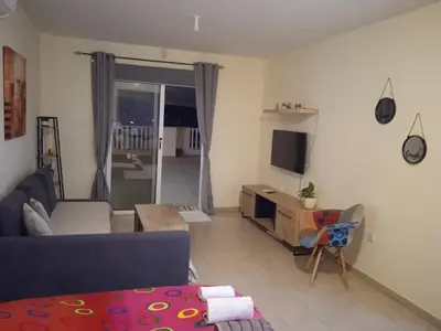 a living room with a couch and a tv at Xylophagou Larnaca Ayia Napa Sunshine Apartments in Xylophaghou