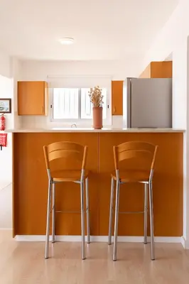 a kitchen with two bar stools at a counter at Blue Penthouse Mackenzie in Larnaka