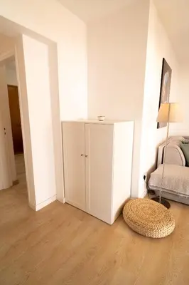 a white bedroom with a bed and a rug on the floor at Blue Penthouse Mackenzie in Larnaka