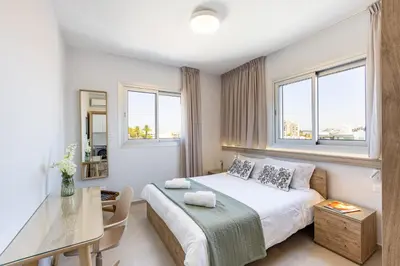 a bedroom with a bed and a table and windows at Attika Residence in Strovolos