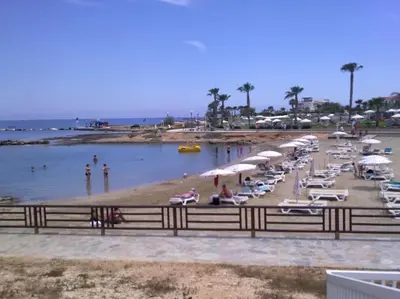 a beach with a bunch of umbrellas and people in the water at Aphrodite Sea View Suite in Protaras
