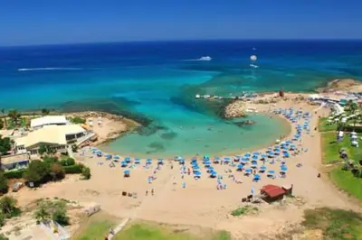 a group of people on a beach with umbrellas at Aphrodite Sea View Suite in Protaras