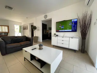 a living room with a couch and a tv on the wall at 13 Crystal Lagoon Villa in Paralimni