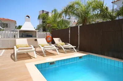 a patio with two chairs and a swimming pool at Villa Artemis - 30m from Pernera Beach in Protaras