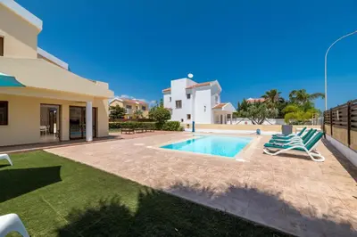 a villa with a swimming pool and two lawn chairs at Villa Sarah in Ayia Napa