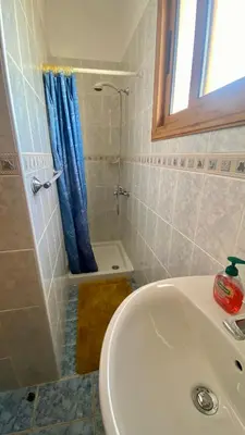 a bathroom with a sink and a shower with a blue curtain at Villa Annalisarose in Ayia Napa