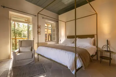 a bedroom with a large bed and a chair at Casa Oliva Guesthouse in Tris Elies