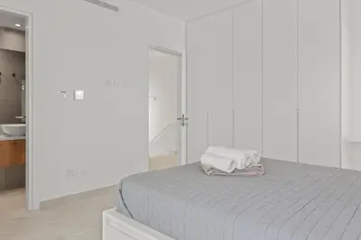 a white bedroom with a bed with a towel on it at Serenity Waves Villa 10 in Sophtadhes