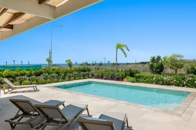 a swimming pool in a villa with chairs and the ocean at Serenity Waves Villa 17 in Larnaka