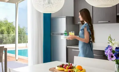 a woman standing in a kitchen holding a plate of food at Dazzling Protaras Villa Villa Akame 3 Bedrooms Beachfront in Protaras