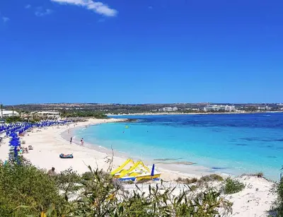a beach with a group of people and the ocean at Dazzling Protaras Villa Villa Akame 3 Bedrooms Beachfront in Protaras
