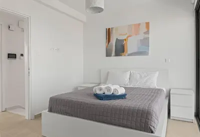 a white bedroom with a bed with two towels on it at Serenity Waves Villa 22 in Larnaka