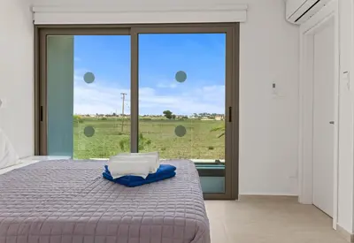 a bedroom with a bed and a large window at Serenity Waves Villa 22 in Larnaka