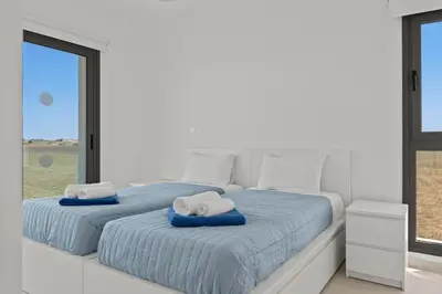 a bedroom with two beds with blue sheets and a window at Serenity Waves Villa 9 in Sophtadhes