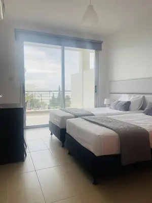 two beds in a room with a large window at Fig Tree View Apartments in Protaras