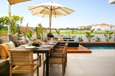 a table with chairs and an umbrella on a patio at Amazing Protaras Villa Villa Lubbock 3 Bedrooms Private Outdoor Pool in Protaras