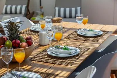 a wooden table with plates and glasses of orange juice at Extraordinary Protaras Villa Villa Leone 3 Bedrooms Private Outdoor Pool in Protaras