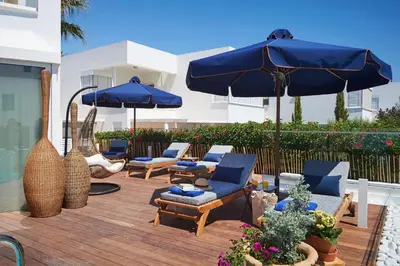 a patio with blue umbrellas and chairs on a wooden deck at Luxury Protaras Villa Villa Najenda 3 Bedrooms Private Outdoor Pool in Protaras