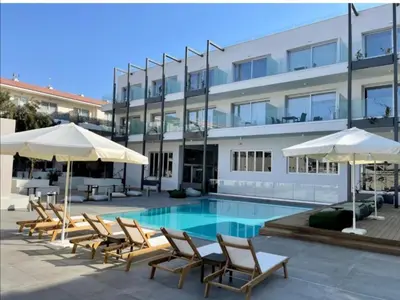 a pool with chairs and umbrellas in front of a building at Mythical Sands - Escape in Paralimni