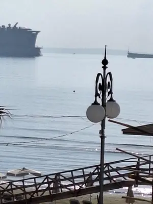 a street light in front of the ocean with a cruise ship at Paradise by the Sea in Larnaka
