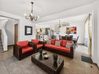 a living room with red couches and a kitchen at Villa Ioli - 3BR Retreat near Kalamies Beach in Protaras
