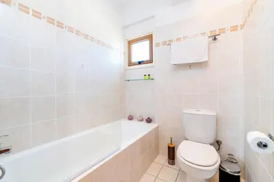 a white bathroom with a toilet and a bath tub at Elena Gardens Villa in Ayia Napa