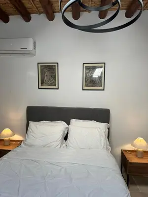 a bedroom with a white bed with two lamps and a chandelier at AROMA DRYOS in Kato Drys