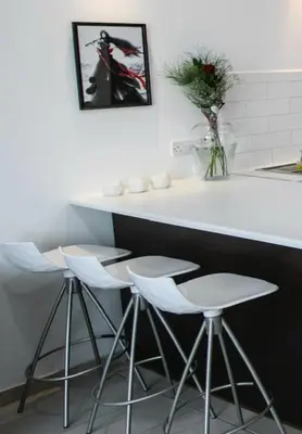 a counter with four stools in a kitchen with a sink at Central cozy apt in quiet area in Engomi in Nicosia