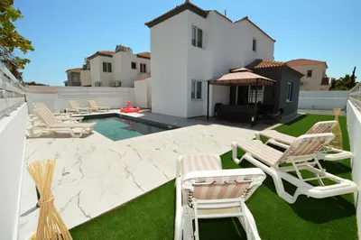 a backyard with chairs and a swimming pool at La Bella Nissi Villa in Ayia Napa
