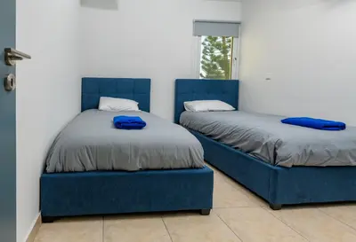 two beds with blue chairs in a room at Olympia Flat 104 in Larnaka