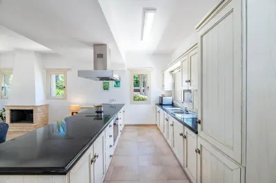 a large kitchen with black countertops and a fireplace at Villa Lindo in Protaras