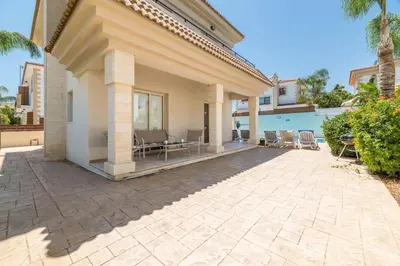 a patio of a house with chairs and trees at Villa Lindo in Protaras
