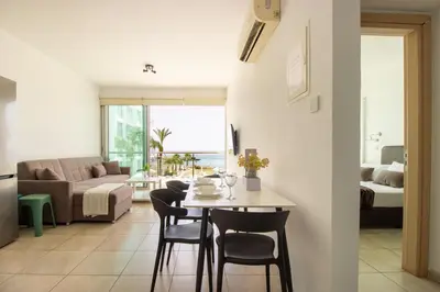 a living room with a table and chairs and a couch at Prime Protaras Seafront Apt in Protaras