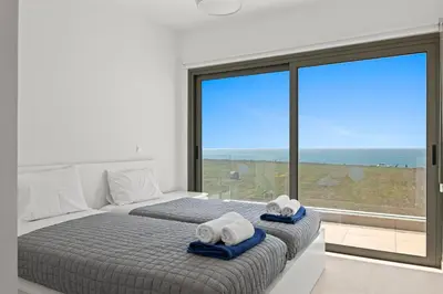 a bedroom with a bed with towels and a large window at Serenity Waves Villa 6 in Sophtadhes