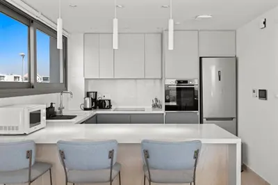 a kitchen with white cabinets and a counter with chairs at Serenity Waves Villa 6 in Sophtadhes