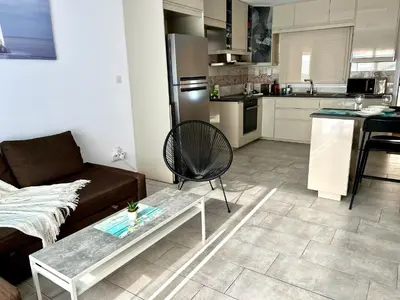 a living room with a couch and a table and a kitchen at Nissi Golden Sands Apartment D01 in Ayia Napa