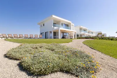 a large white house with chairs in front of it at Serenity Waves Villa 1 in Sophtadhes