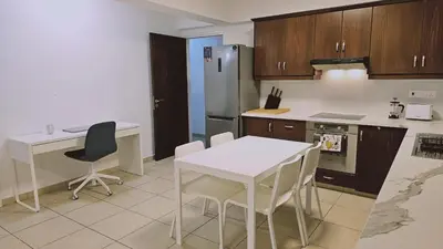 a kitchen with a white table and a refrigerator at STAY Skyline Nest in Larnaka