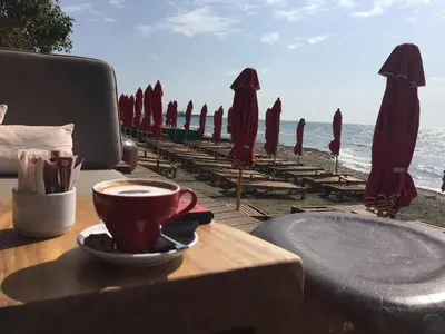 a cup of coffee sitting on a table near the beach at Modern 1 bedroom sea view beach apartment in Limassol
