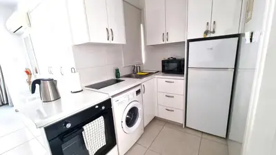 a white kitchen with a refrigerator and a dishwasher at Stylish Studio - 2 Minutes from Kastella Beach in Larnaka