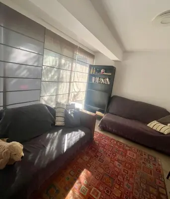 a living room with a black couch and a window at A Detached Floor in Parekklisha