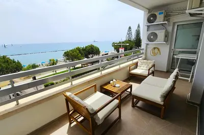 a balcony with chairs and a table and a view of the ocean at Molos Beachfront City-Centre in Limassol