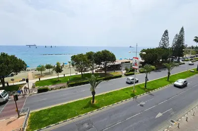 a street with cars driving down a road next to the ocean at Molos Beachfront City-Centre in Limassol