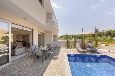 a patio with a table and chairs and a swimming pool at Protaras Mythical Seas in Protaras